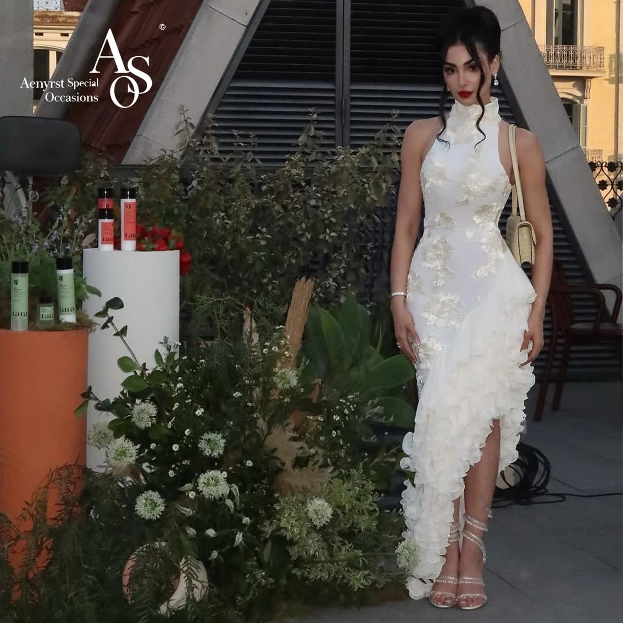 Ivory halter-neck sleeveless floor-length formal gown featuring an asymmetrical hem embroidery and a printed design